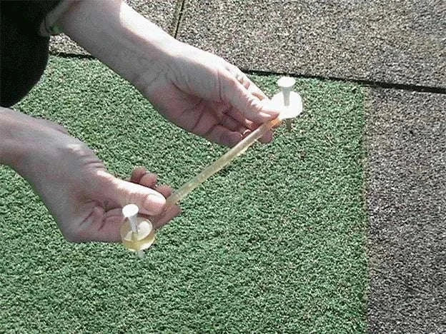 Hands holding the NeverLostGolf Tee Saver ™ on a golf mat.