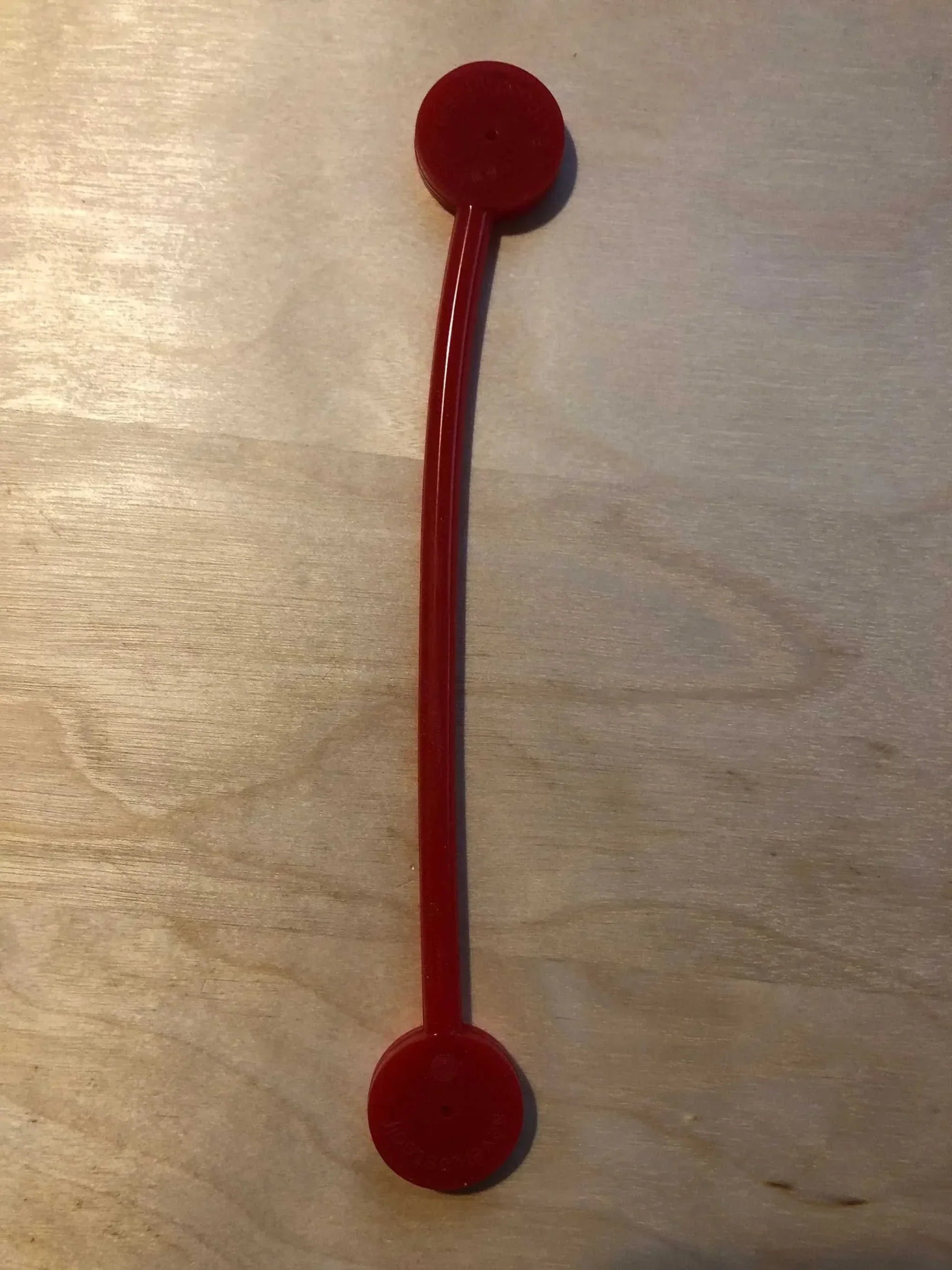 Red NeverLostGolf Tee Saver on wooden surface.